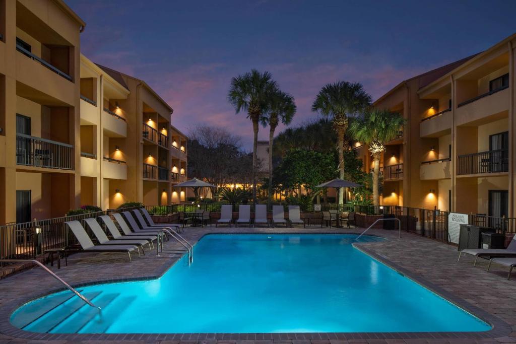 a swimming pool at night with chairs and a hotel at Courtyard by Marriott Jacksonville at the Mayo Clinic Campus/Beaches in Jacksonville