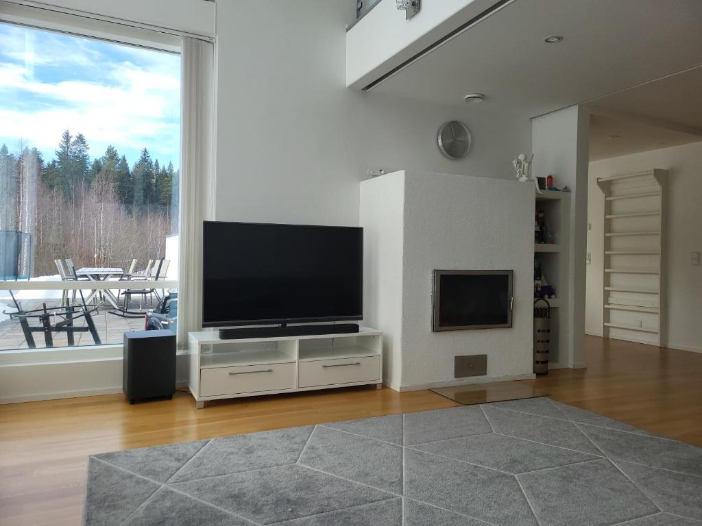 sala de estar con TV de pantalla plana en un soporte en Rauhallisella paikalla upea iso omakotitalo., en Kajaani