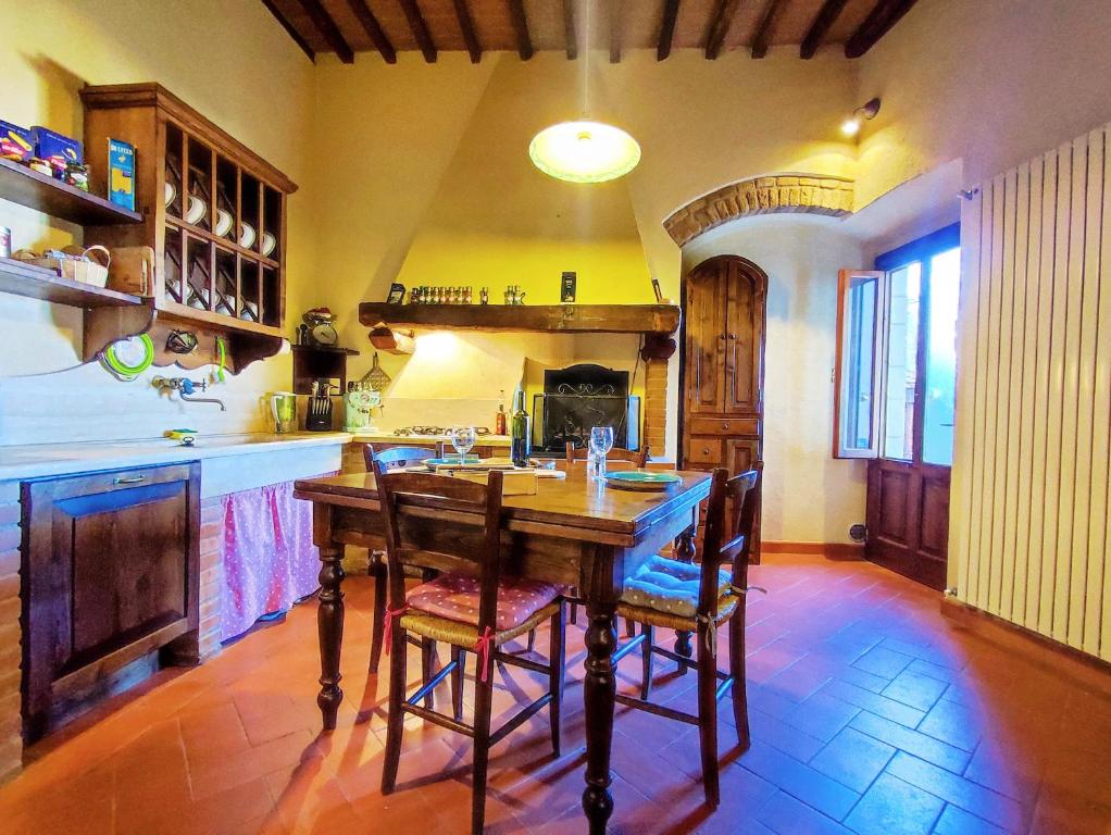 Casa Matteo San Gimignano Apartments في سان جيمنيانو: مطبخ كبير مع طاولة وكراسي خشبية