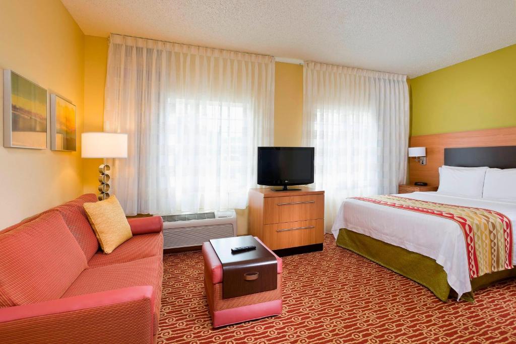 a hotel room with a bed and a couch and a tv at TownePlace Suites by Marriott Dallas Bedford in Bedford