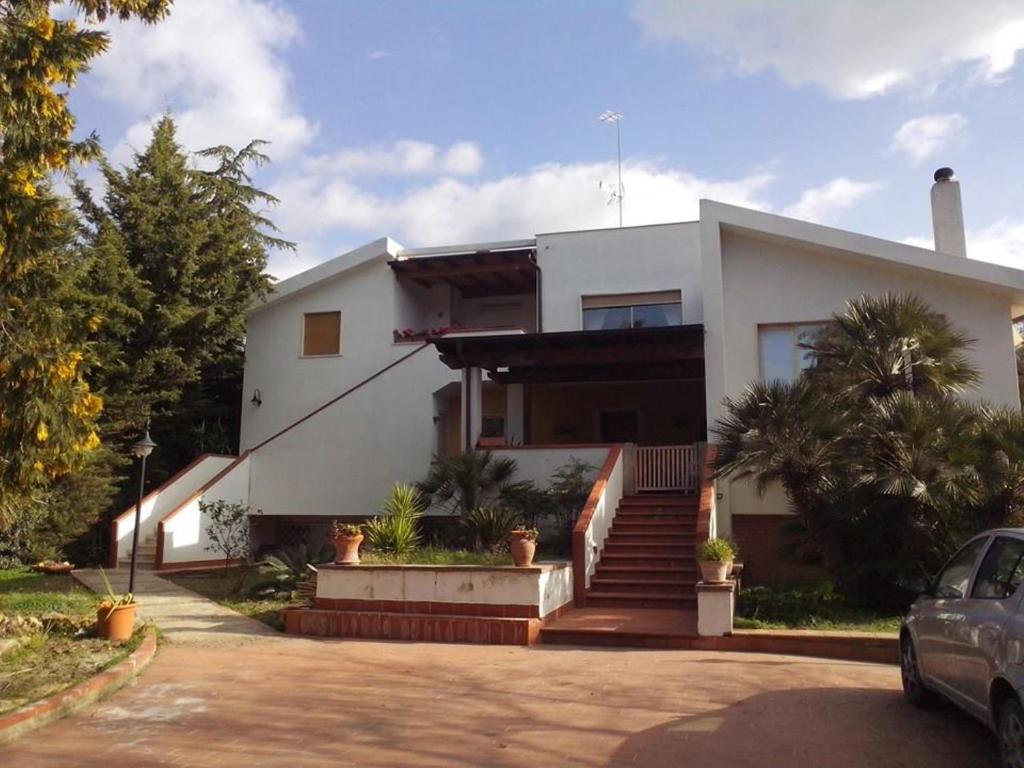 een wit huis met een auto ervoor geparkeerd bij B&B Pian del Lago in Caltanissetta