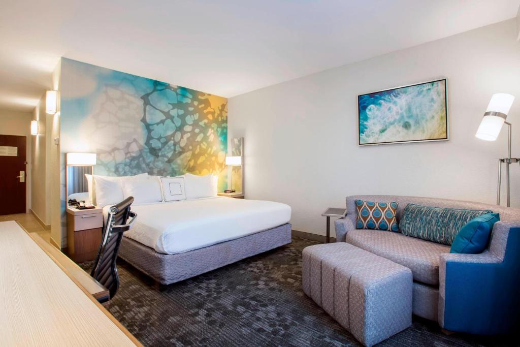 ein Hotelzimmer mit einem Bett und einem Sofa in der Unterkunft Courtyard by Marriott Fort Lauderdale Coral Springs in Coral Springs