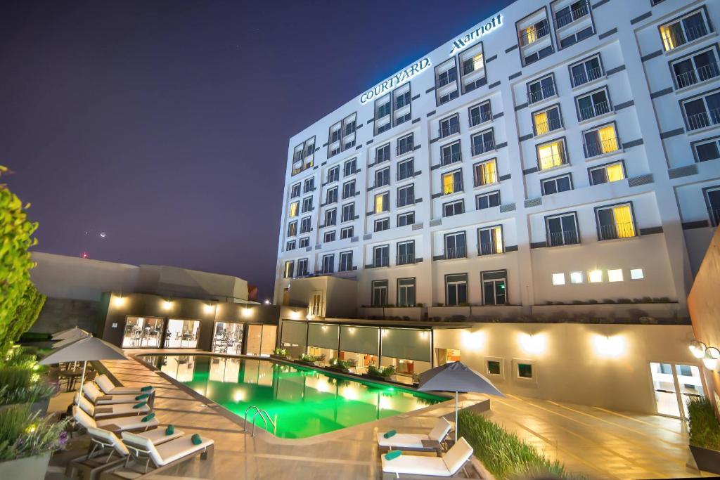 a hotel with a swimming pool in front of a building at Courtyard by Marriott Puebla Las Animas in Puebla