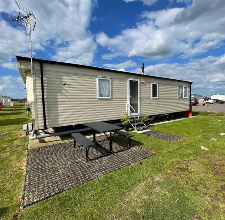 a tiny house with a picnic table in a yard at Modern 6 Berth Caravan With Wifi At St Osyth Beach In Essex Ref 28051fv in Clacton-on-Sea