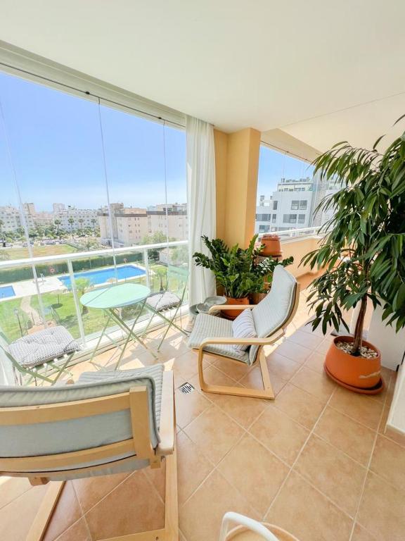salon z krzesłami i balkonem z basenem w obiekcie Bright apartment with terrace, pool and beach w mieście Torremolinos