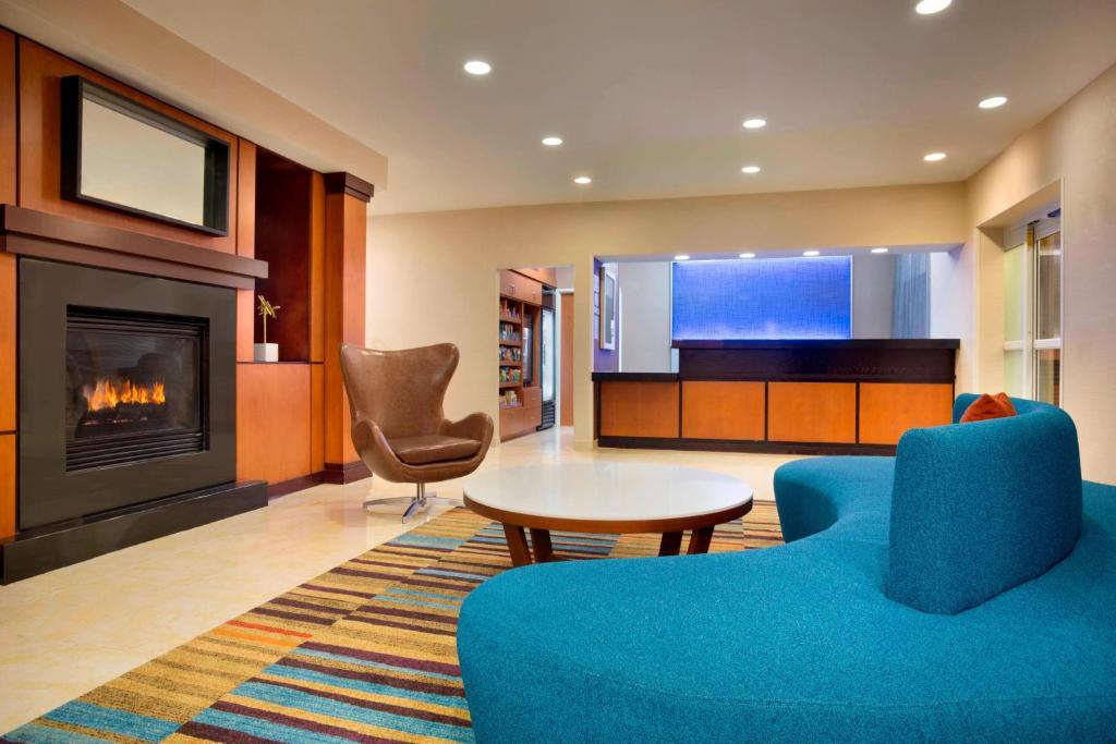 een woonkamer met een open haard en een blauwe bank bij Fairfield Inn & Suites by Marriott Dallas Plano in Plano