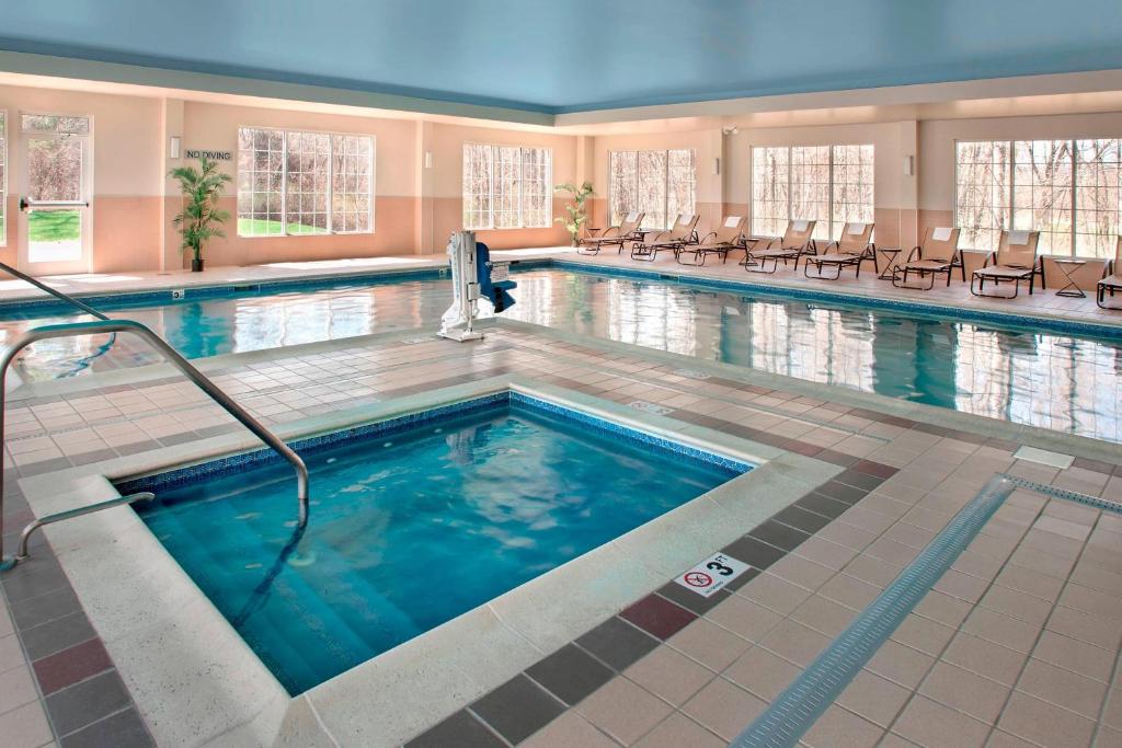 einen Pool in einem Hotel mit Stühlen und Tischen in der Unterkunft Fairfield Inn & Suites by Marriott Great Barrington Lenox/Berkshires in Great Barrington