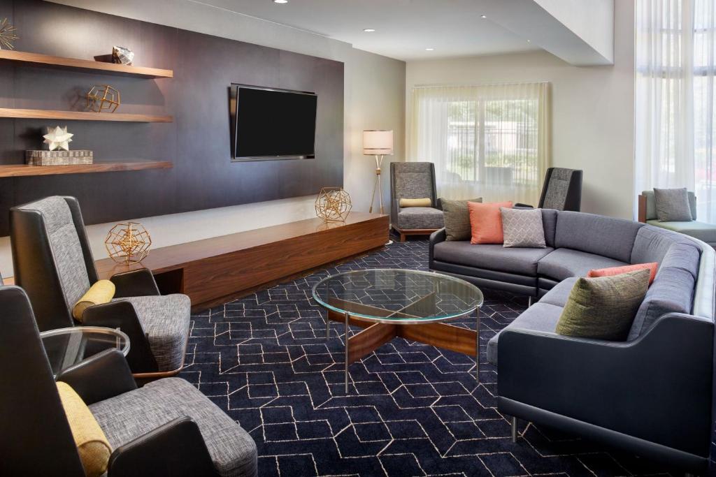 a living room with couches and a flat screen tv at Courtyard by Marriott Atlanta Alpharetta in Alpharetta
