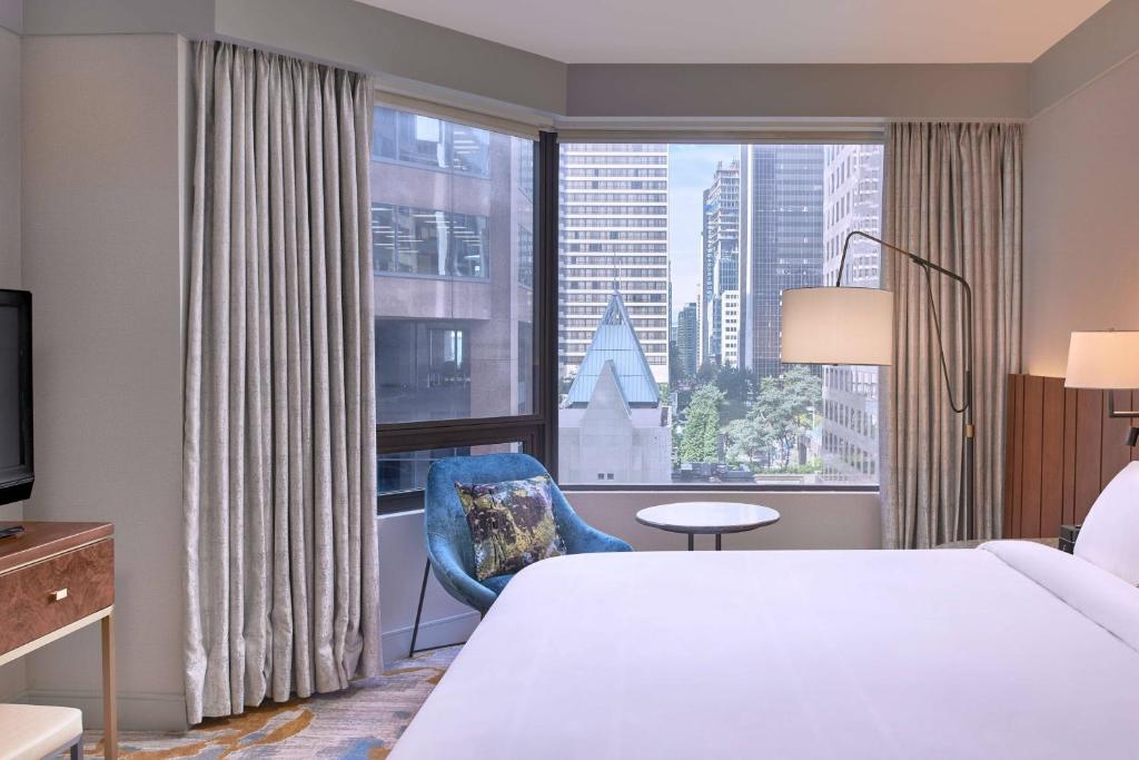 a hotel room with a bed and a large window at Metropolitan Hotel Vancouver in Vancouver