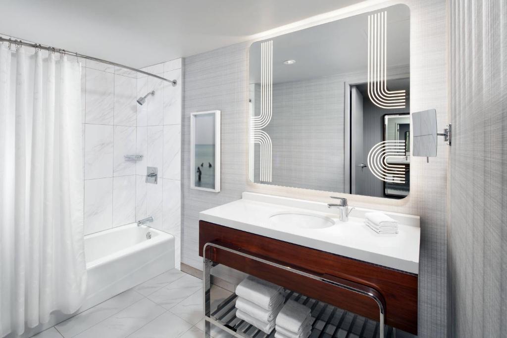a bathroom with a sink and a tub and a mirror at Sheraton Grand Los Angeles in Los Angeles