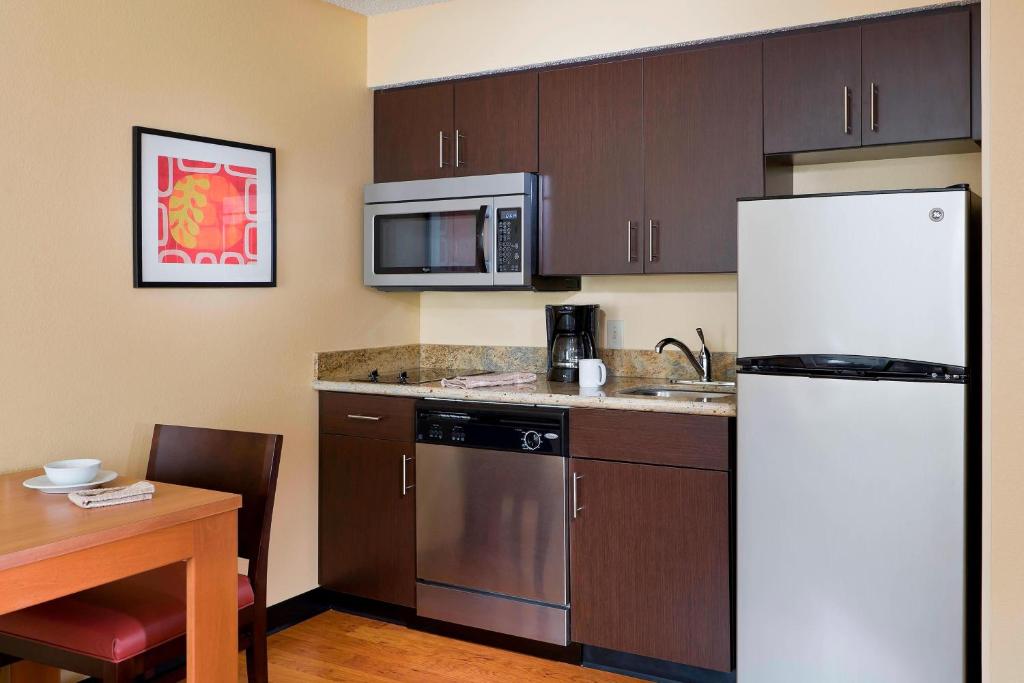a kitchen with a white refrigerator and a table at TownePlace Suites Houston Brookhollow in Houston