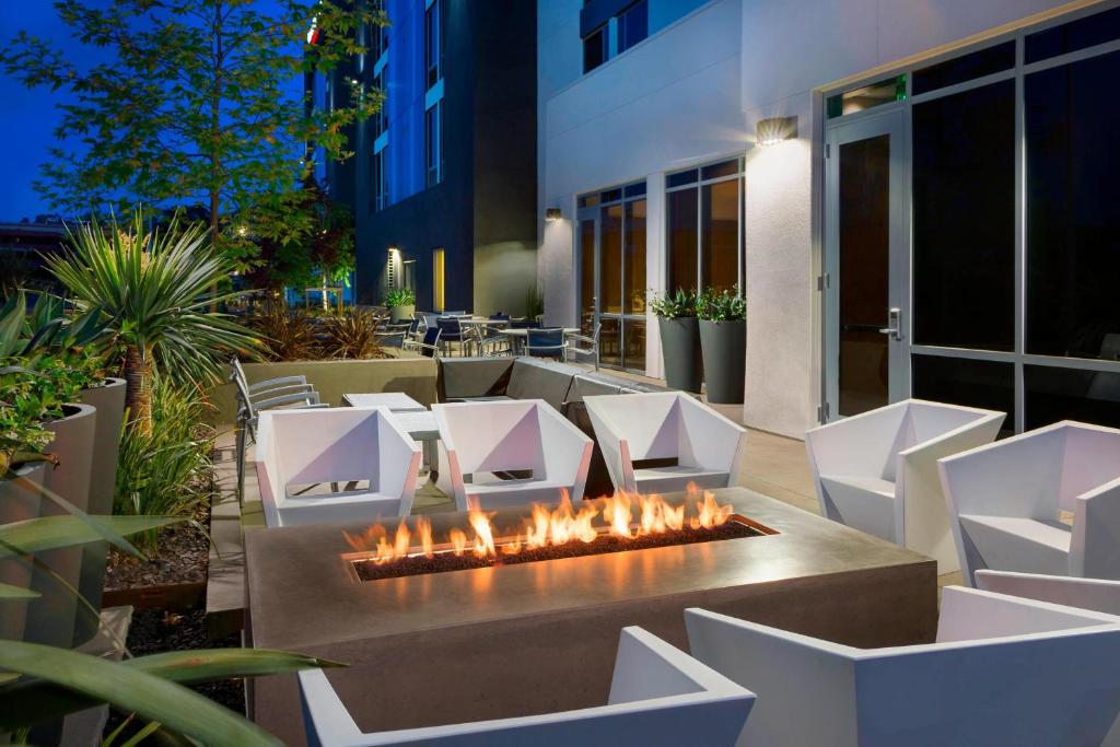 eine Terrasse mit einer Feuerstelle und weißen Stühlen in der Unterkunft SpringHill Suites by Marriott San Diego Mission Valley in San Diego