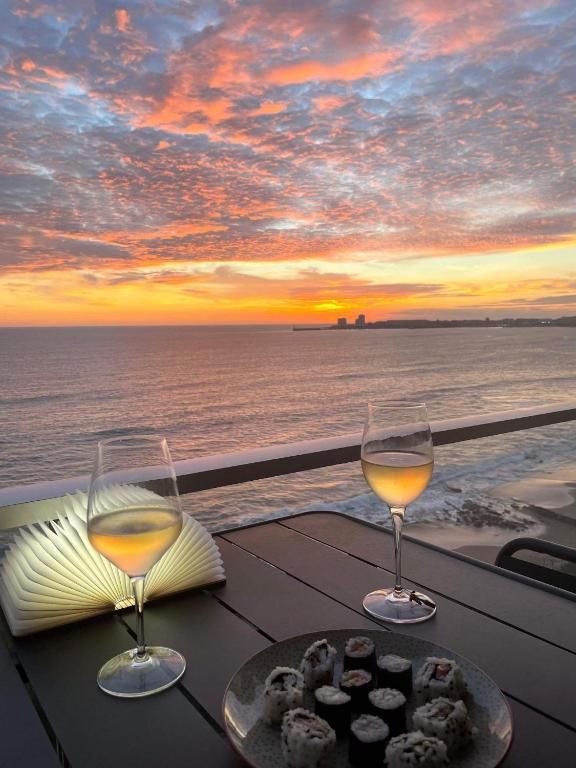 - une table avec deux verres de vin et une assiette de nourriture dans l'établissement La Petite Case - Face Mer, à Les Sables-dʼOlonne
