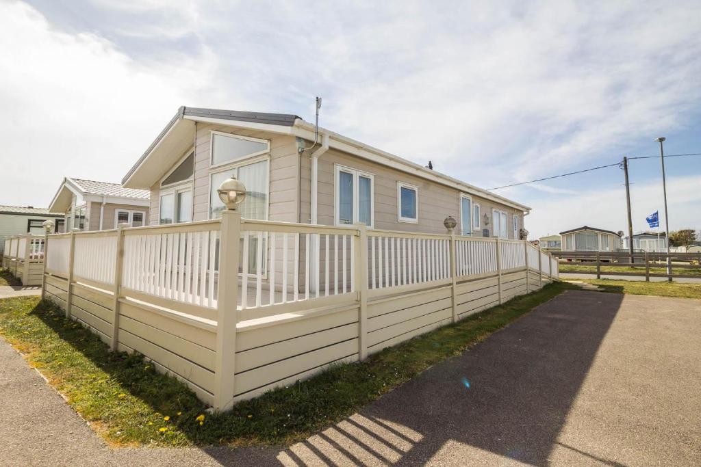 a house with a white fence in front of it at Luxury Platinum Lodge At Suffolk Sands Holiday Park Ref 45009mv in Felixstowe