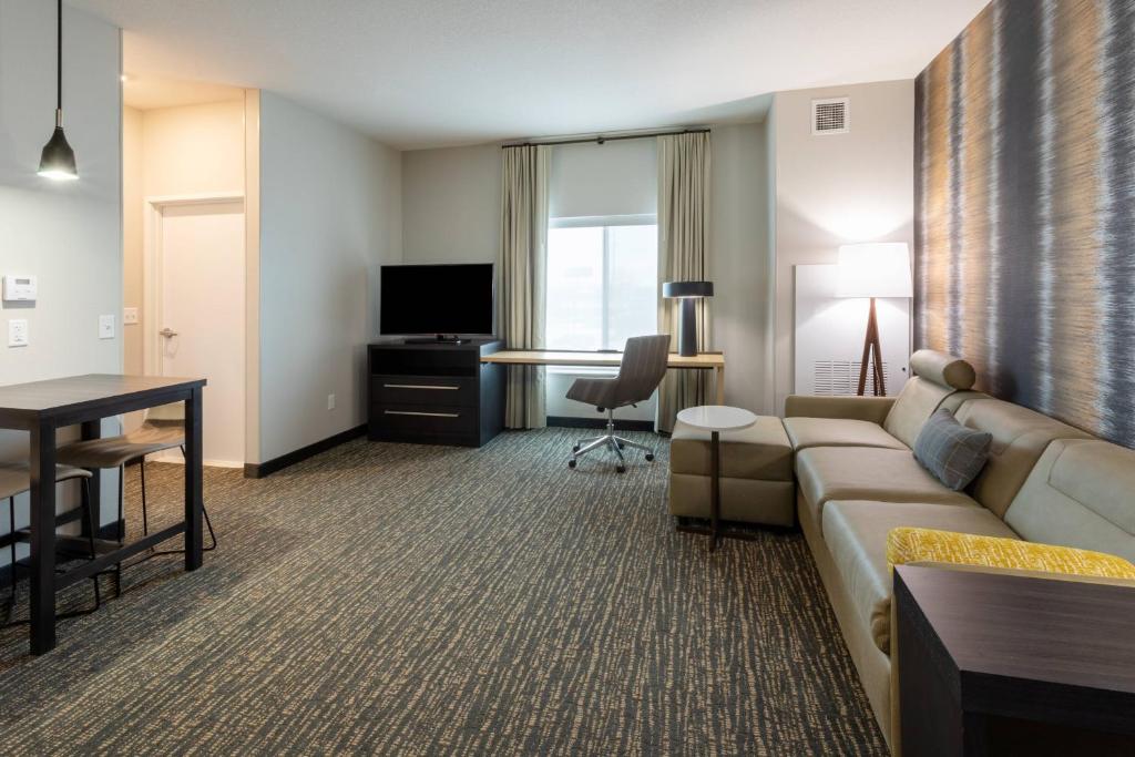 a living room with a couch and a table and a television at Residence Inn by Marriott St. Cloud in Waite Park