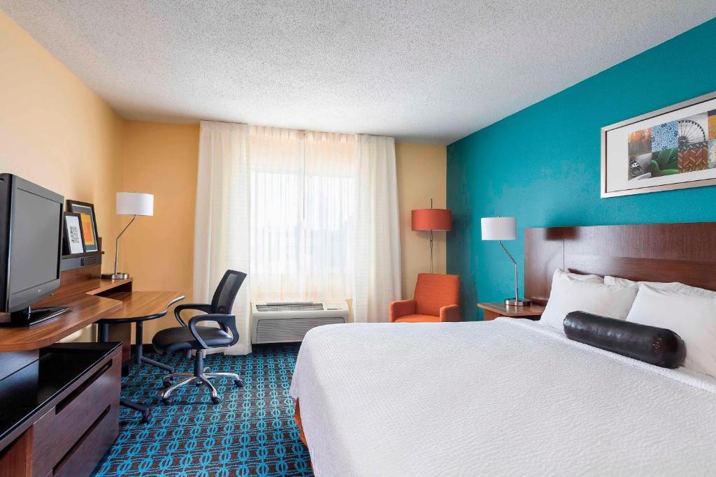 a hotel room with a bed and a desk and a television at Fairfield Inn & Suites Holland in Holland