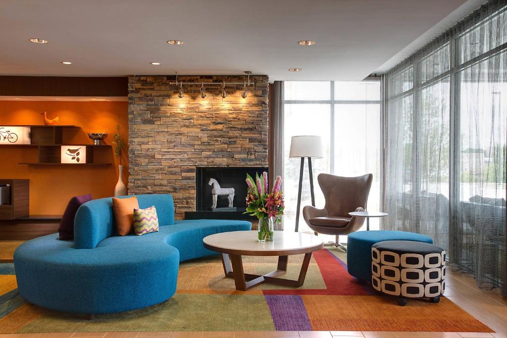 a living room with blue furniture and a fireplace at Fairfield Inn & Suites by Marriott Dallas West/I-30 in Dallas