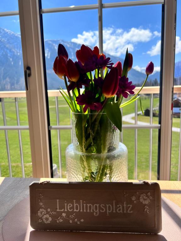 un jarrón lleno de flores rojas sentado en una mesa en S‘Lieblingsplatzl, en Bad Aussee