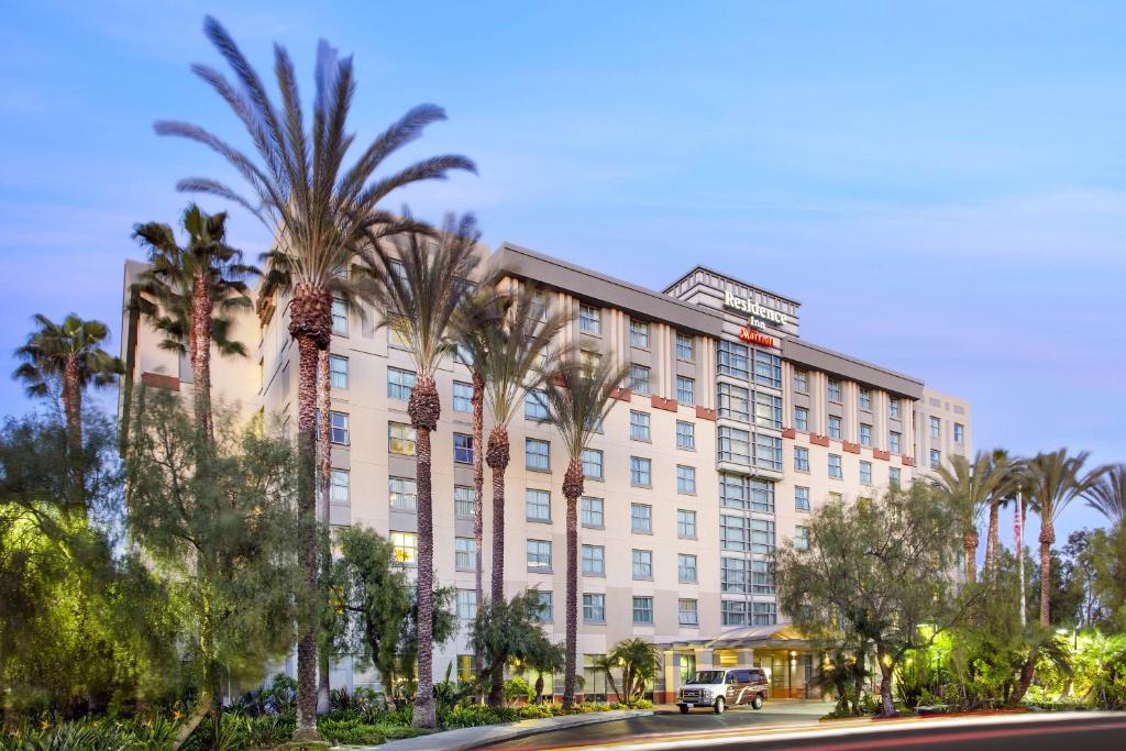 a building with palm trees in front of a street at Residence Inn Irvine John Wayne Airport Orange County in Irvine