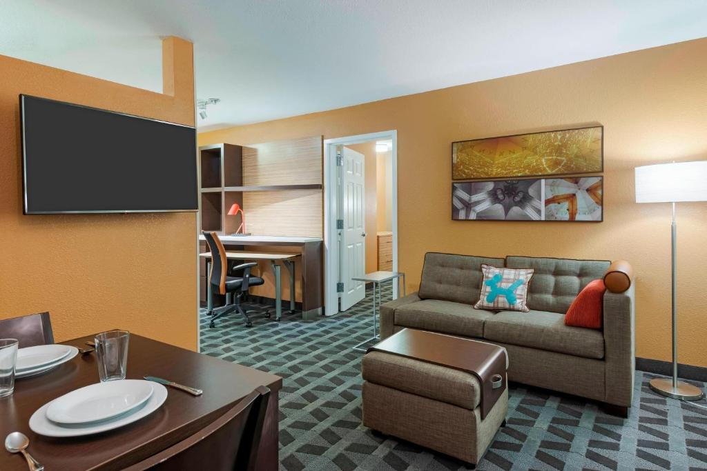 TownePlace Suites Savannah Midtown في سافانا: غرفة معيشة مع أريكة وتلفزيون