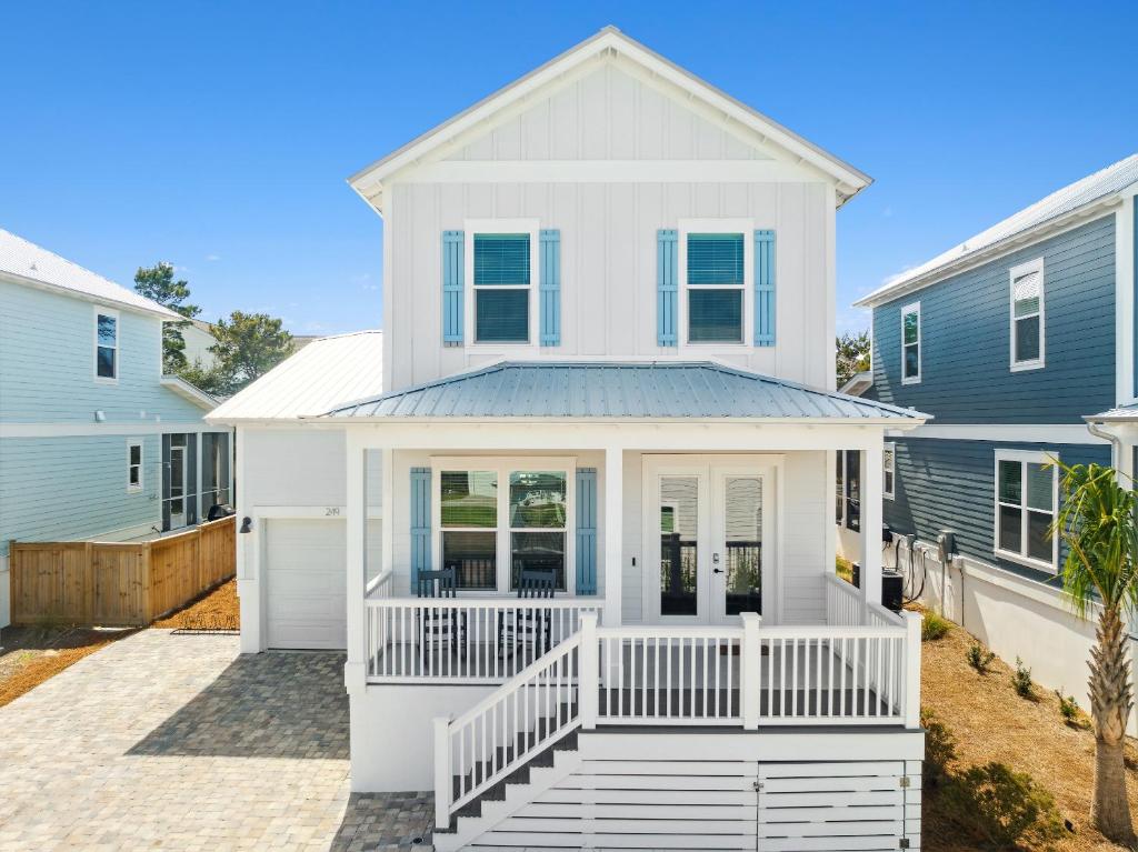 a white house with a porch in front of two houses at 30A Beach House - Mira Bella in Rosemary Beach