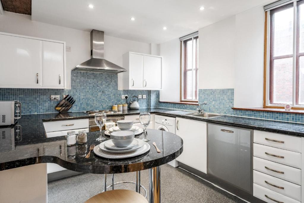 a kitchen with white cabinets and a black counter top at Lively Liverpool Living -1BR Flat Near Cavern Club - Pass The Keys in Liverpool