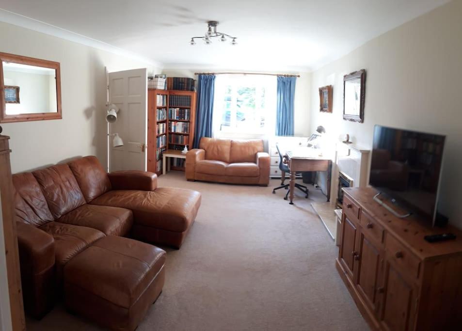 a living room with a brown leather couch and a desk at Entire house, Crambeck,Welburn, near Castle Howard in Welburn