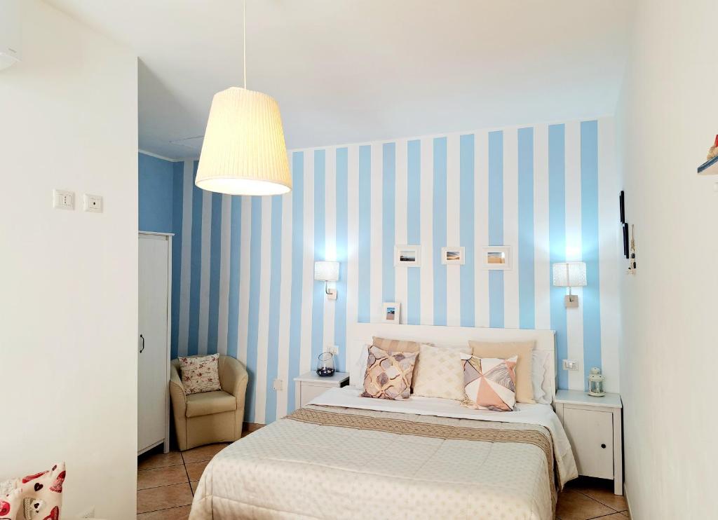 um quarto com uma cama e uma parede com riscas azuis em Superior Apartment le Case del Sole Licata em Licata