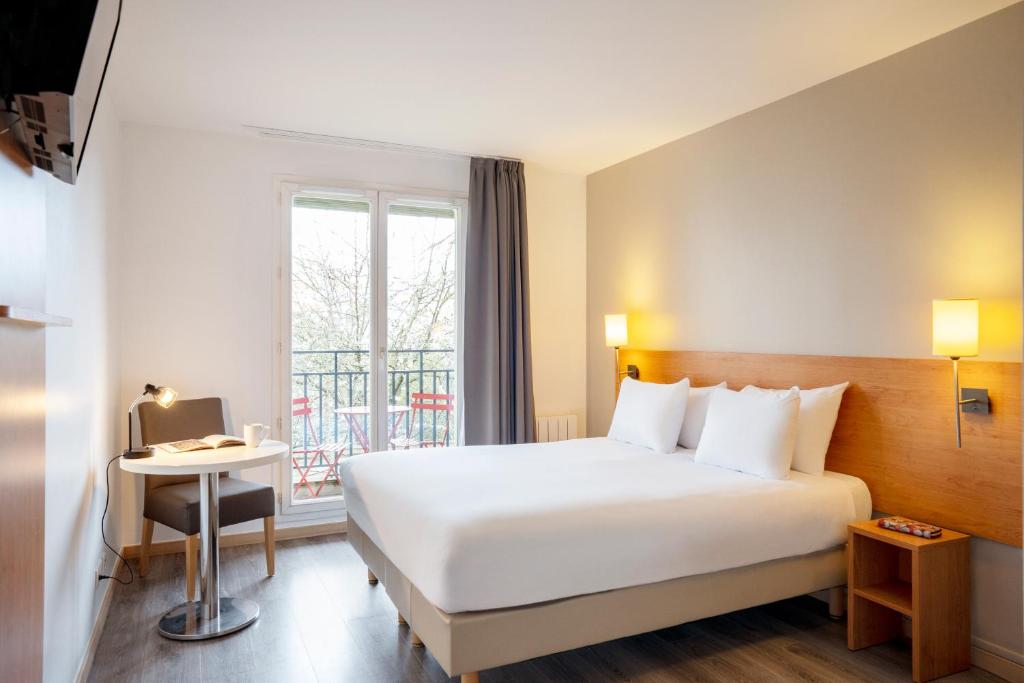 a hotel room with a white bed and a window at Séjours & Affaires Créteil Le Magistere in Créteil