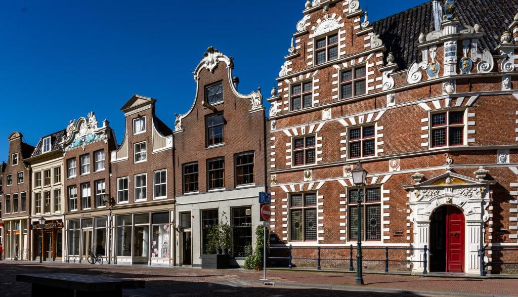 een groot bakstenen gebouw met een rode deur op een straat bij De Ginkgo in het hart van Hoorn in Hoorn