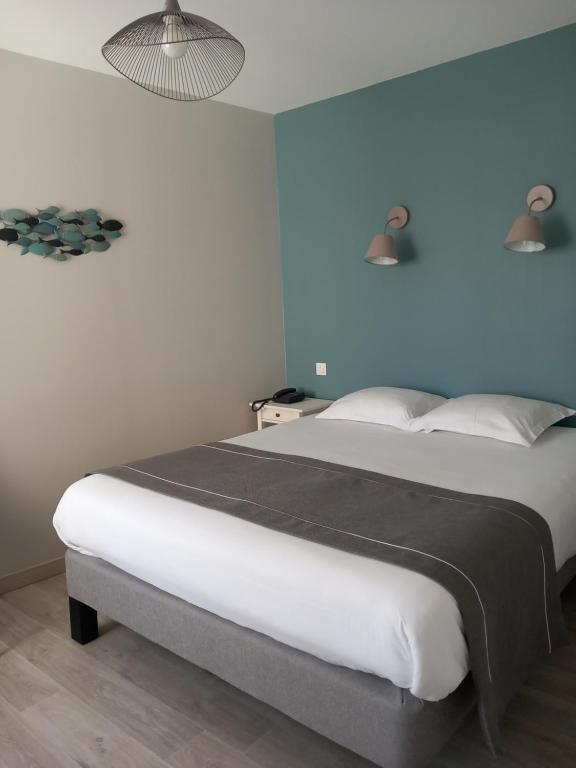 um quarto com uma cama grande e uma parede azul em Logis Hermitage em Perros-Guirec