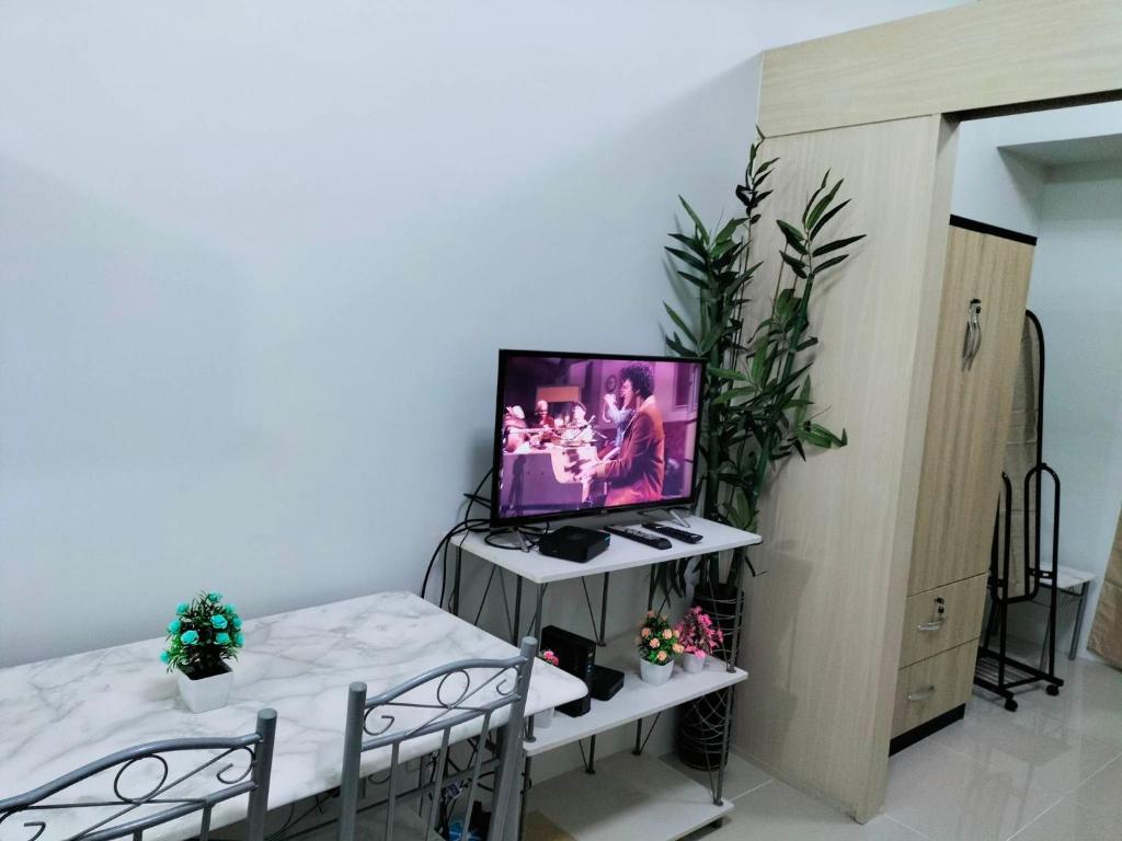 sala de estar con TV y mesa con sillas en JAZZ DREAM CONDOTEL WITH BALCONY AND SWIMMING POOL, en Manila
