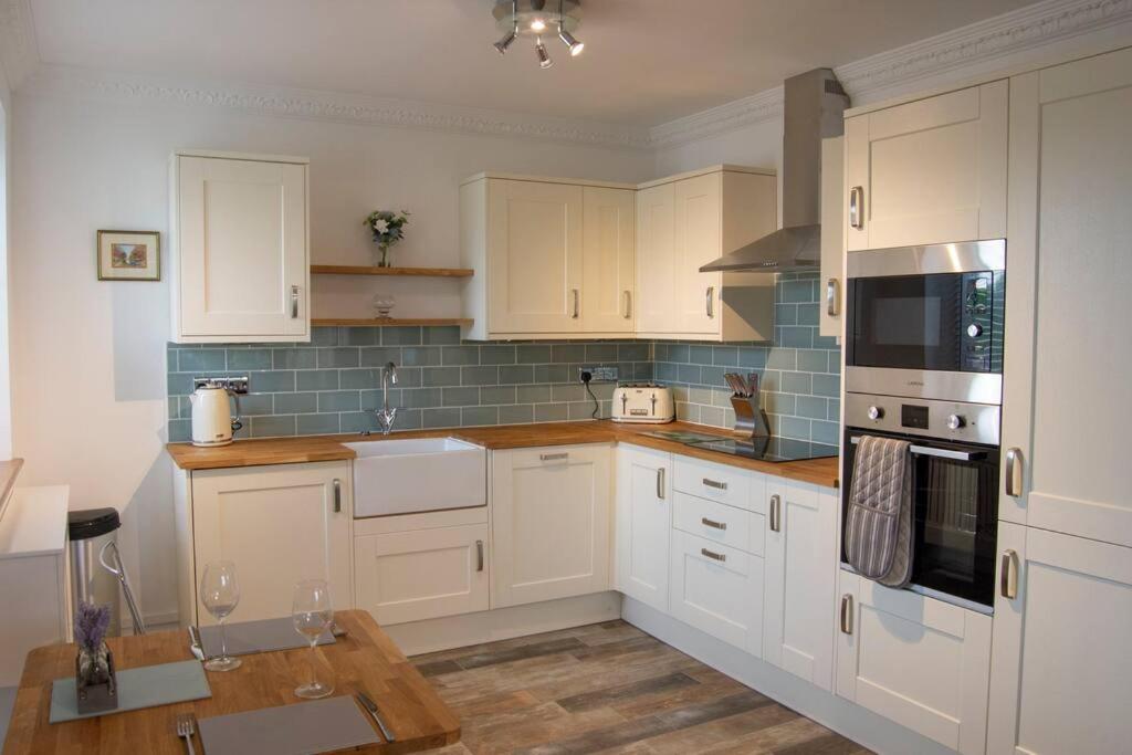 eine Küche mit weißen Schränken und einem Holztisch in der Unterkunft Grapevine Getaway in Lincolnshire