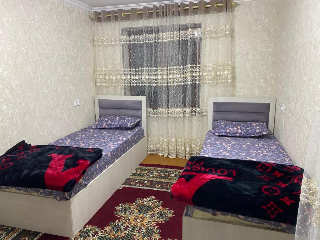1 dormitorio con 2 camas y ventana en MehmonServis1, en Samarkand