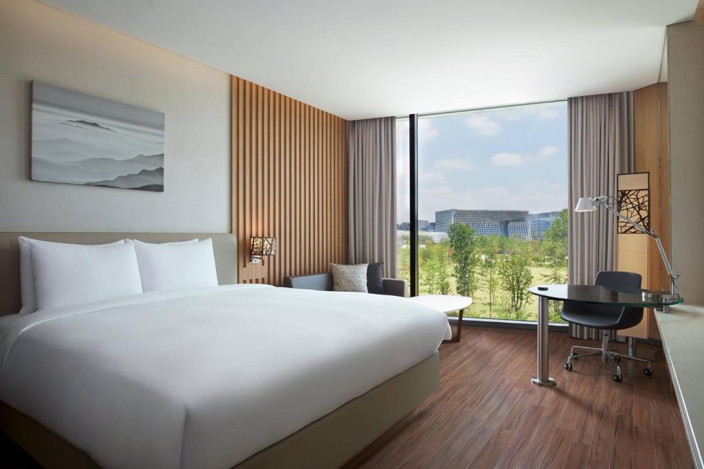 ソウルにあるコートヤード バイ マリオット ソウル ボタニック パークのベッドと大きな窓が備わるホテルルームです。
