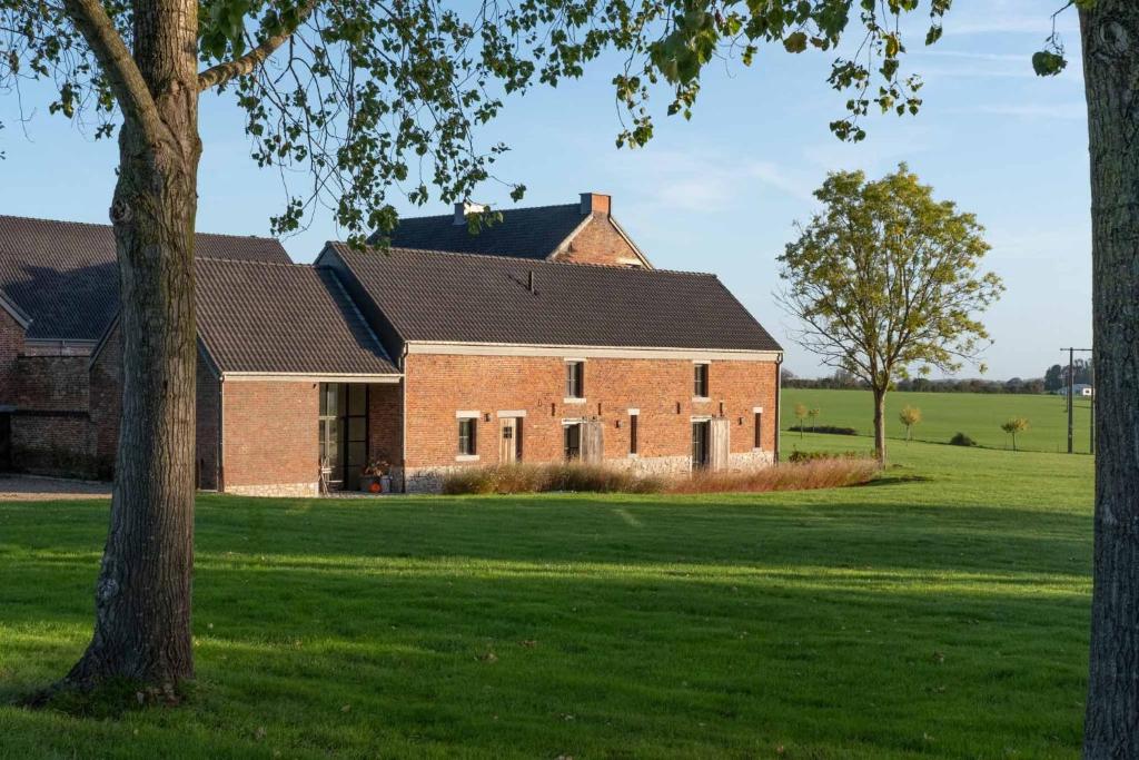 a large brick building in a field of grass at Chambres de Gilberoux in Floreffe