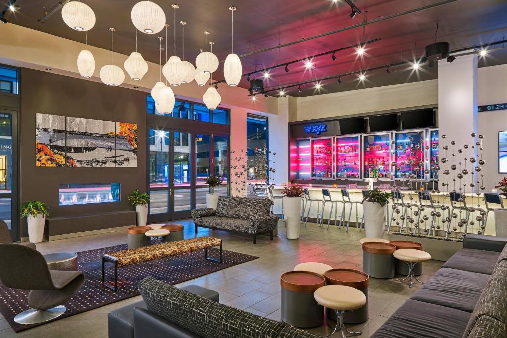 a lobby with couches and chairs and a bar at Aloft South Bend in South Bend
