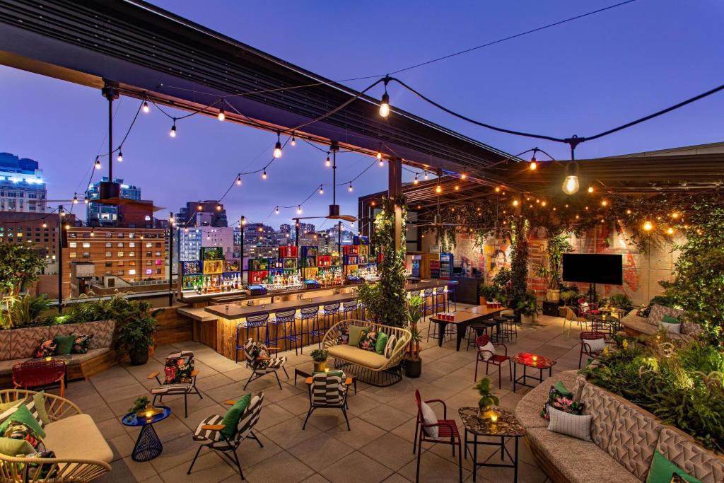 a rooftop patio with tables and chairs and lights at Moxy NYC East Village in New York