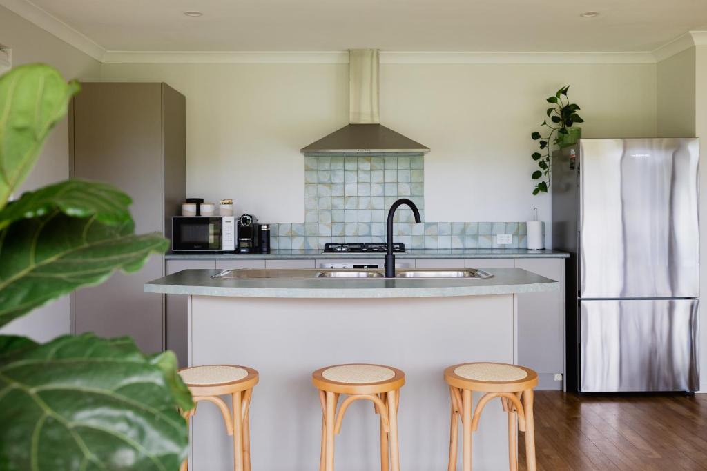 a kitchen with three stools in front of a sink at Djilba Cottage at Windance in Yallingup