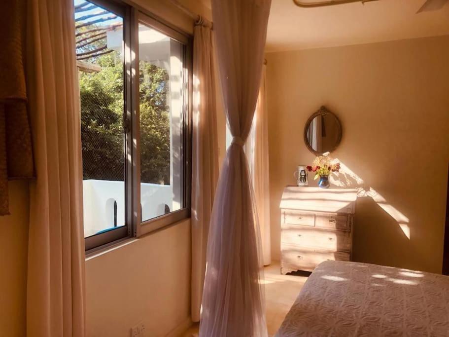 a bedroom with a bed and a window with a tub at The Shore House Diani - 2 Bedroom Villa with a pool in Galu