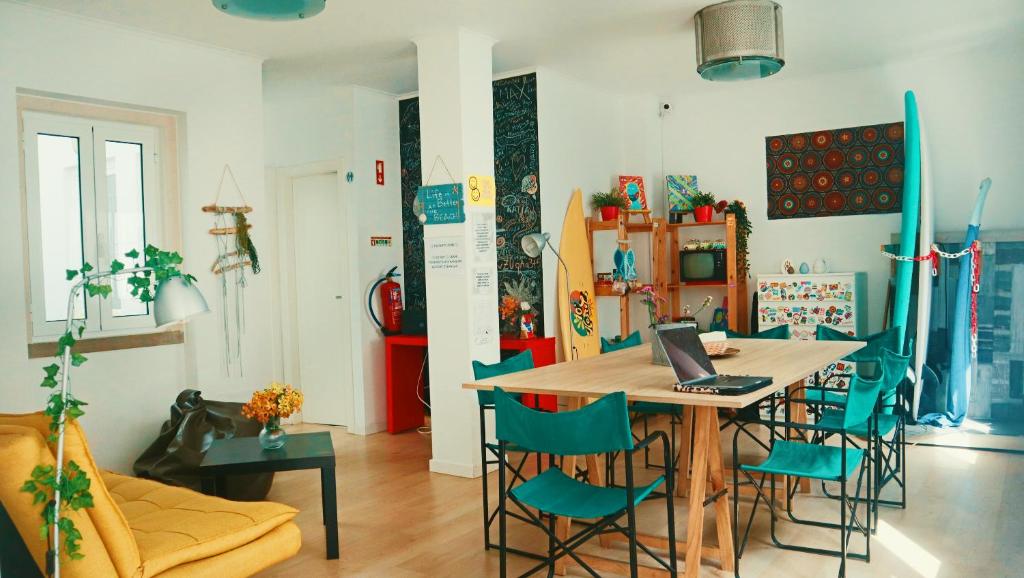 uma sala de jantar com uma mesa e cadeiras com um computador portátil em 70's Hostel na Ericeira