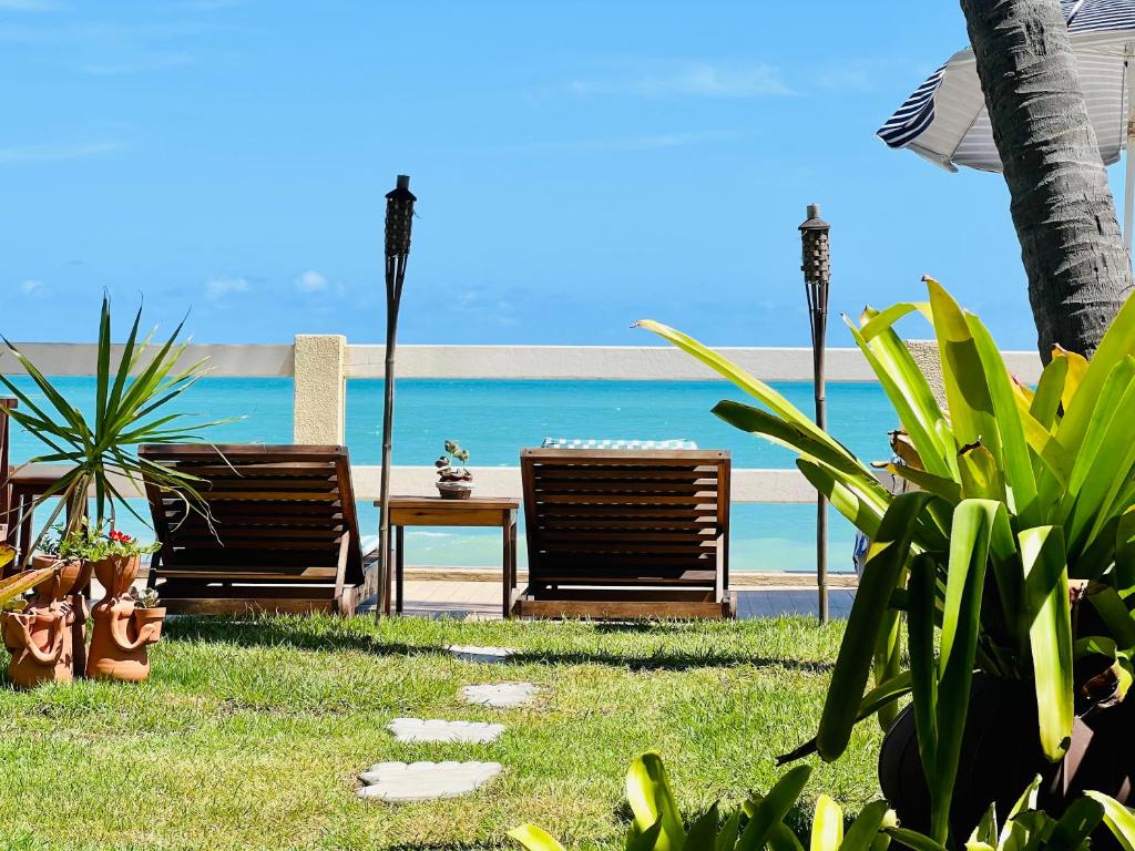 dwa krzesła i stół przed plażą w obiekcie Paraíso na areia da praia w mieście Maceió