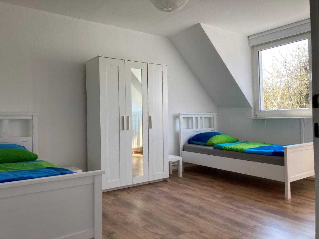 a white bedroom with two beds and a window at gemütliche Altbauwohnung im Wuppertaler Westen in Wuppertal