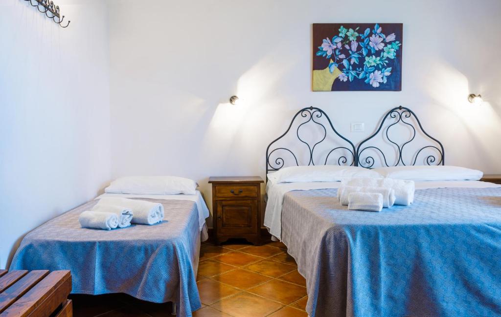 two beds in a room with blue sheets at Casale Ginisara in Castellammare del Golfo