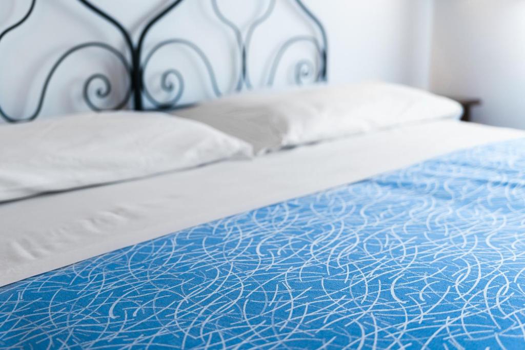 a bed with blue and white sheets and pillows at Casale Ginisara in Castellammare del Golfo