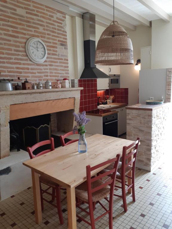 a kitchen with a wooden table with chairs and a fireplace at Bastida in Saint-Macaire