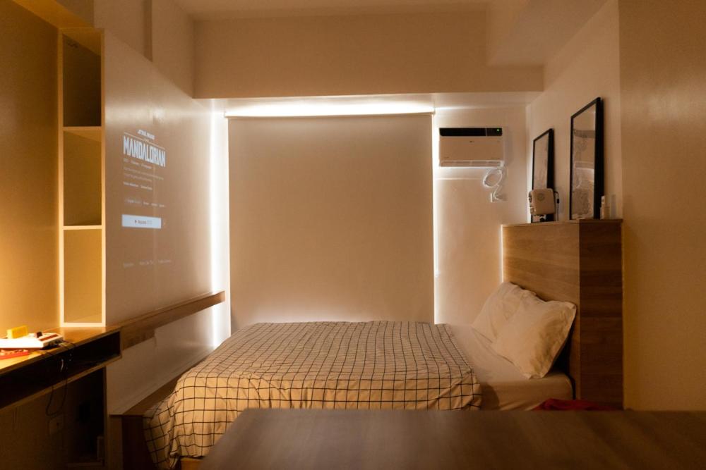 a small room with a bed and a refrigerator at Modern Japanese inspired studio at Avida Towers Atria in Iloilo City