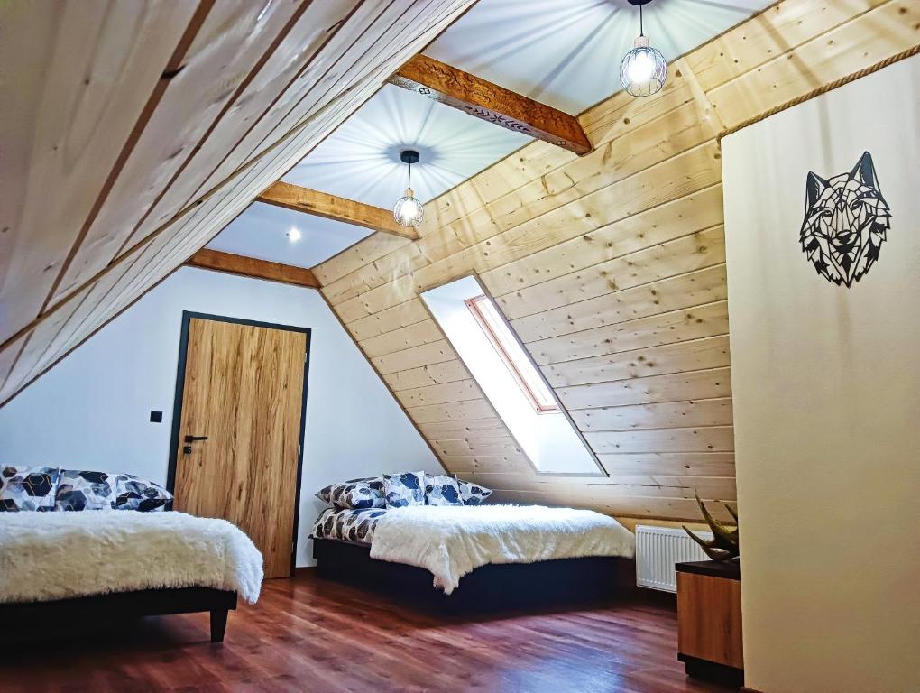 2 bedden in een kamer met houten plafonds bij Apartament SKORUSINKA w pobliżu Chochołowskich Term in Witów