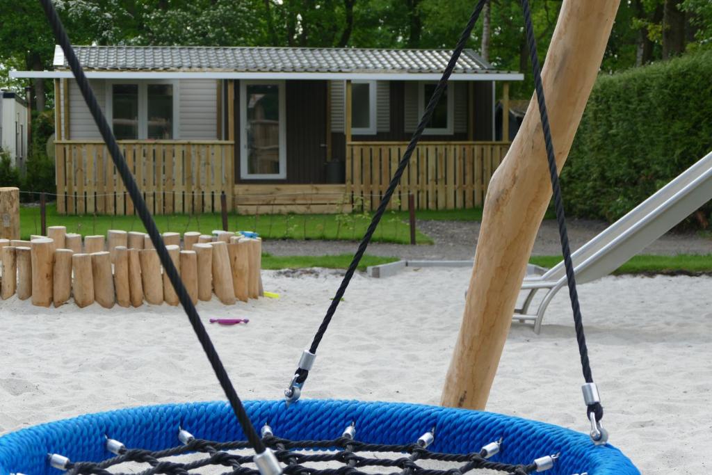 a swing in a playground with a house in the background at VerandaChalet 6p centrally located in National Park, Swimming pool in Wateren
