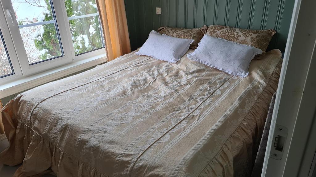 a bed in a bedroom with two windows at Verningen Apartment in Larvik